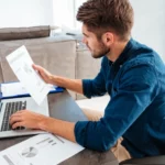 Man analyseert financiële statistieken op een vel papier aan een bureau.
